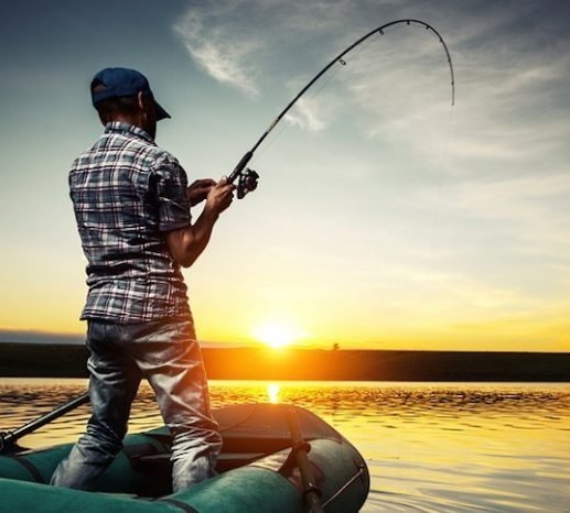 Um pescador fisgando um peixe, ao por do sol, em um dos rios do Mato Grosso